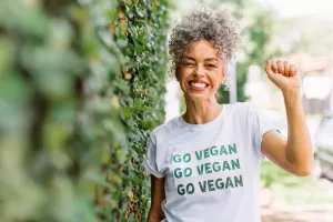 mulher em meio a natureza usando uma camisa escrita "go vegan" comemorando o dia mundial do veganismo